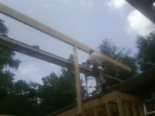 Carpenter setting a ridge beam over a new addition frame — Ice Dam Removal by Roofing Brothers in Clay