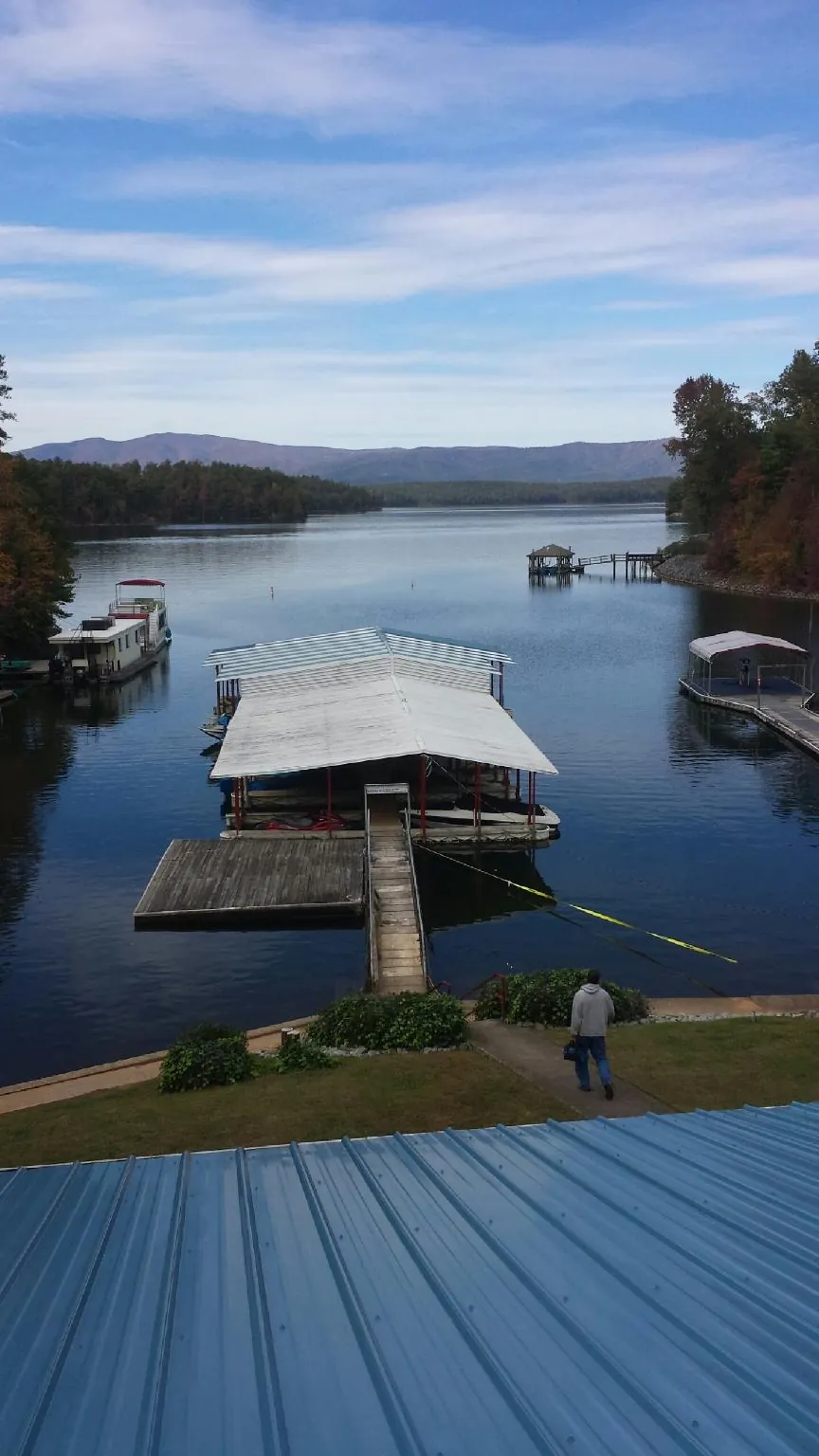 View across a lake from a newly installed blue metal roof in Clay