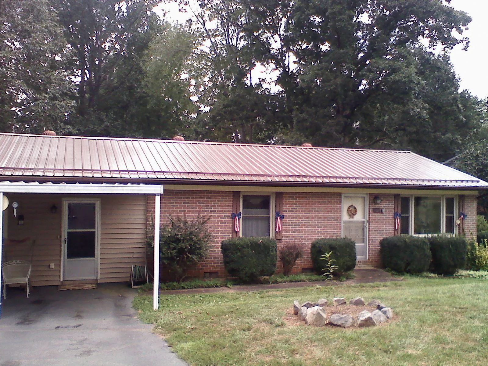 Bronze metal roof and carport on a brick ranch home — Roof Repair work by our crew in Clay