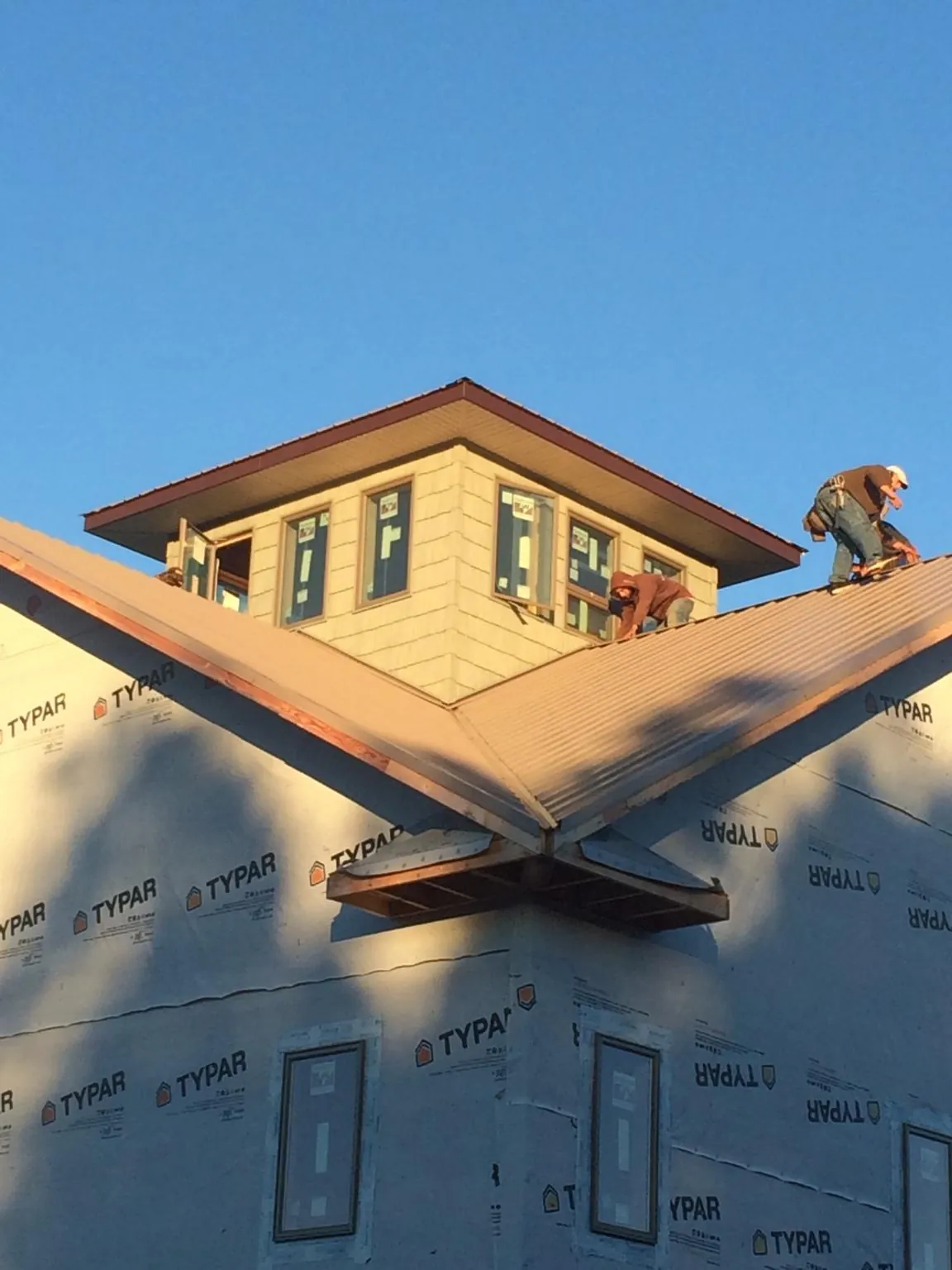 Roofers working around a rooftop cupola on a new metal roof at sunset — Roof Waterproofing in Clay by Roofing Brothers